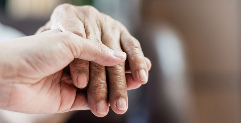 hospice social worker holding dying patient's hand