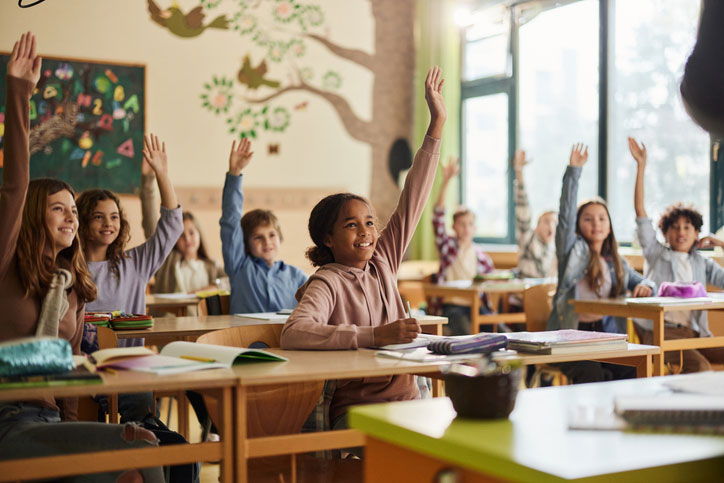 school kids with hands raised