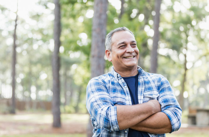 older man smiling in the woods