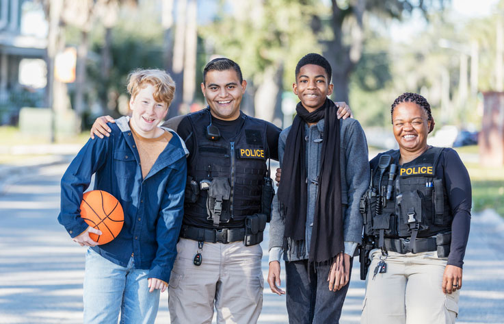 police officers hanging at the park with teen boys playing basketball