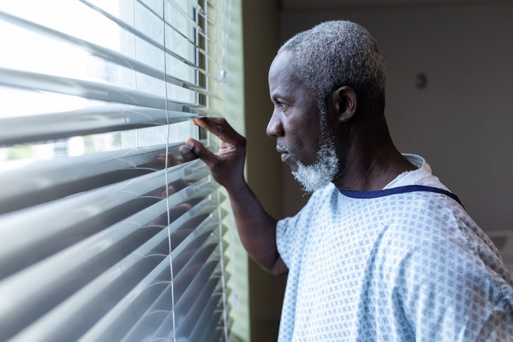 elderly patient looking out the window blinds