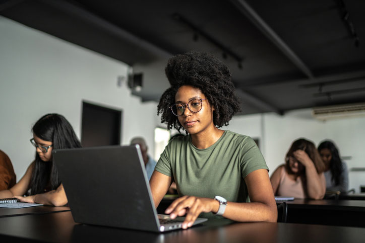 young woman working hard on laptop in classroom