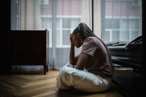 depressed young woman on the floor of her apartment