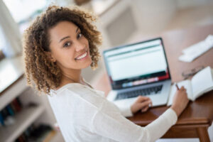 young woman looking up from computer to smile