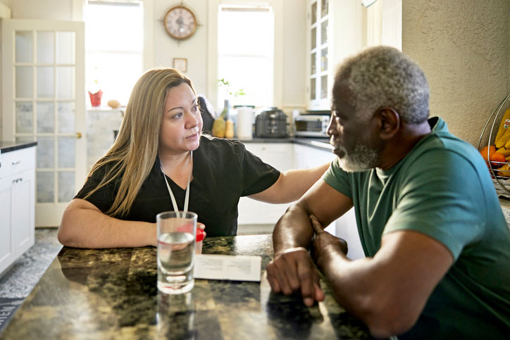 social worker talking with elderly male patient