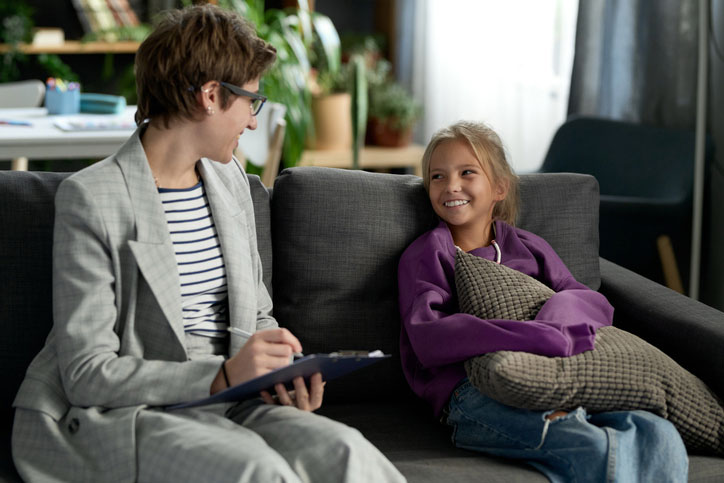 young girl talking with social worker on sofa