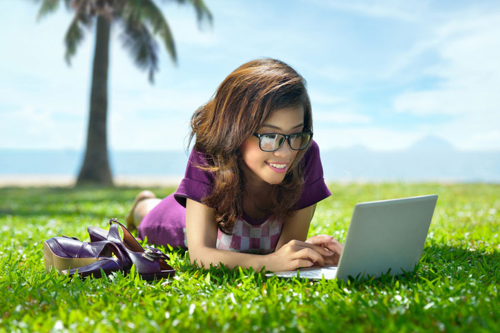 young woman on laptop at the beach