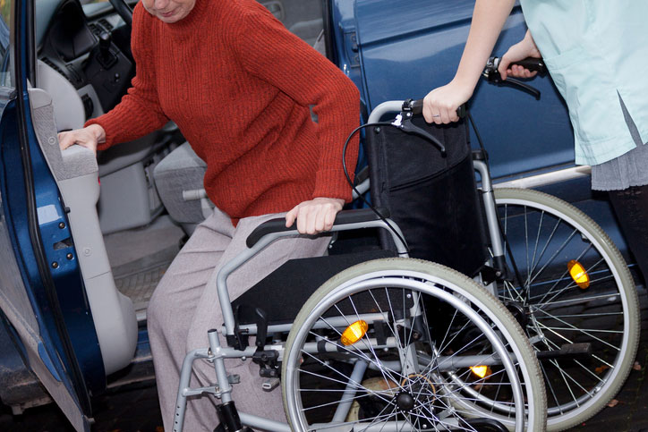 helping elderly woman into her wheelchair