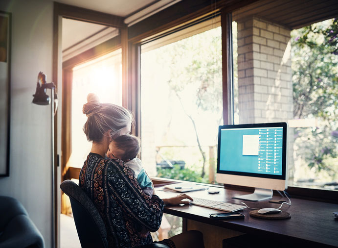 mother holding baby while on her computer at home